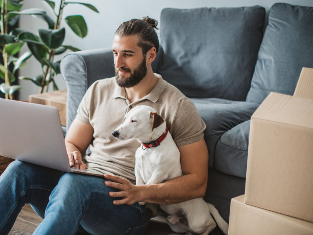 A young man with his dog on a laptop learning about the conveyancing journey and home ownership